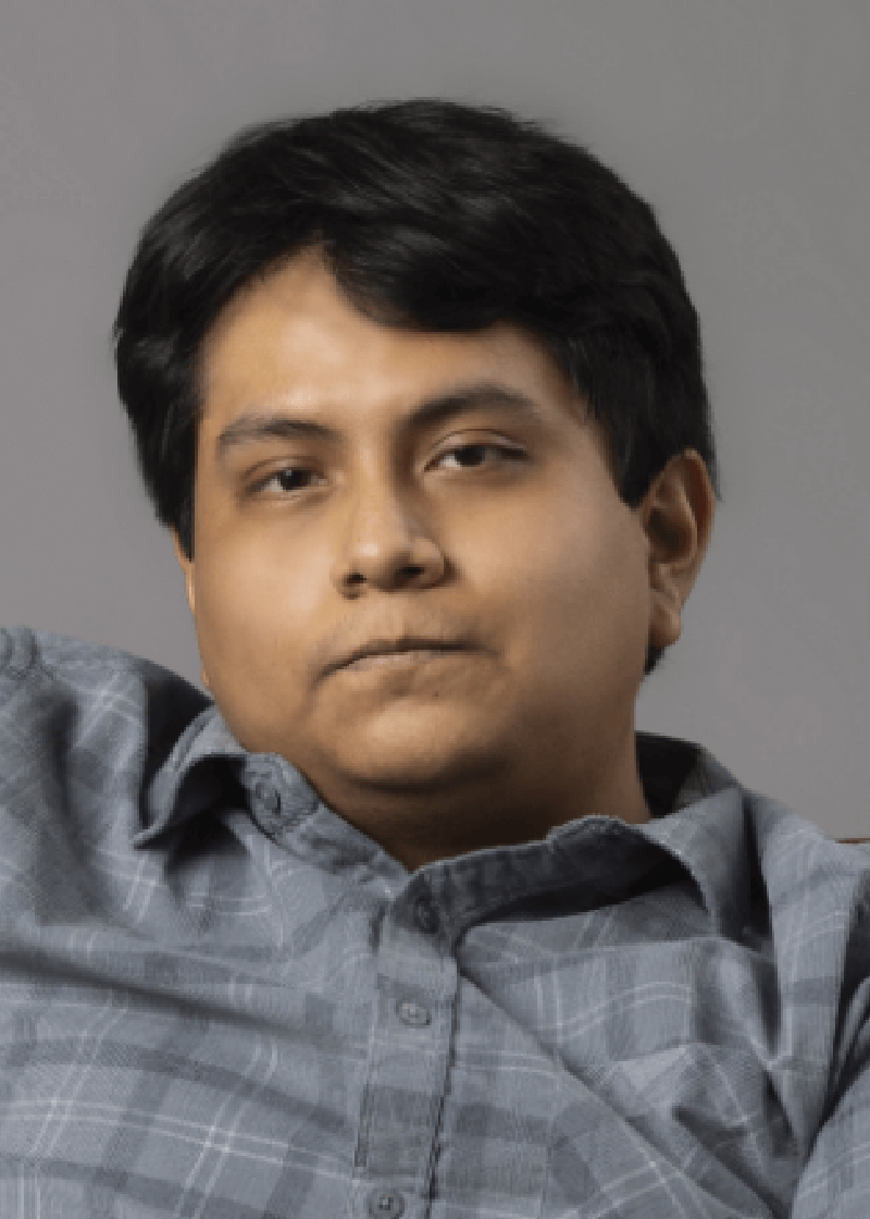 Franco Quispe A young man with dark hair wearing a gray plaid shirt looks directly at the camera with a neutral expression.