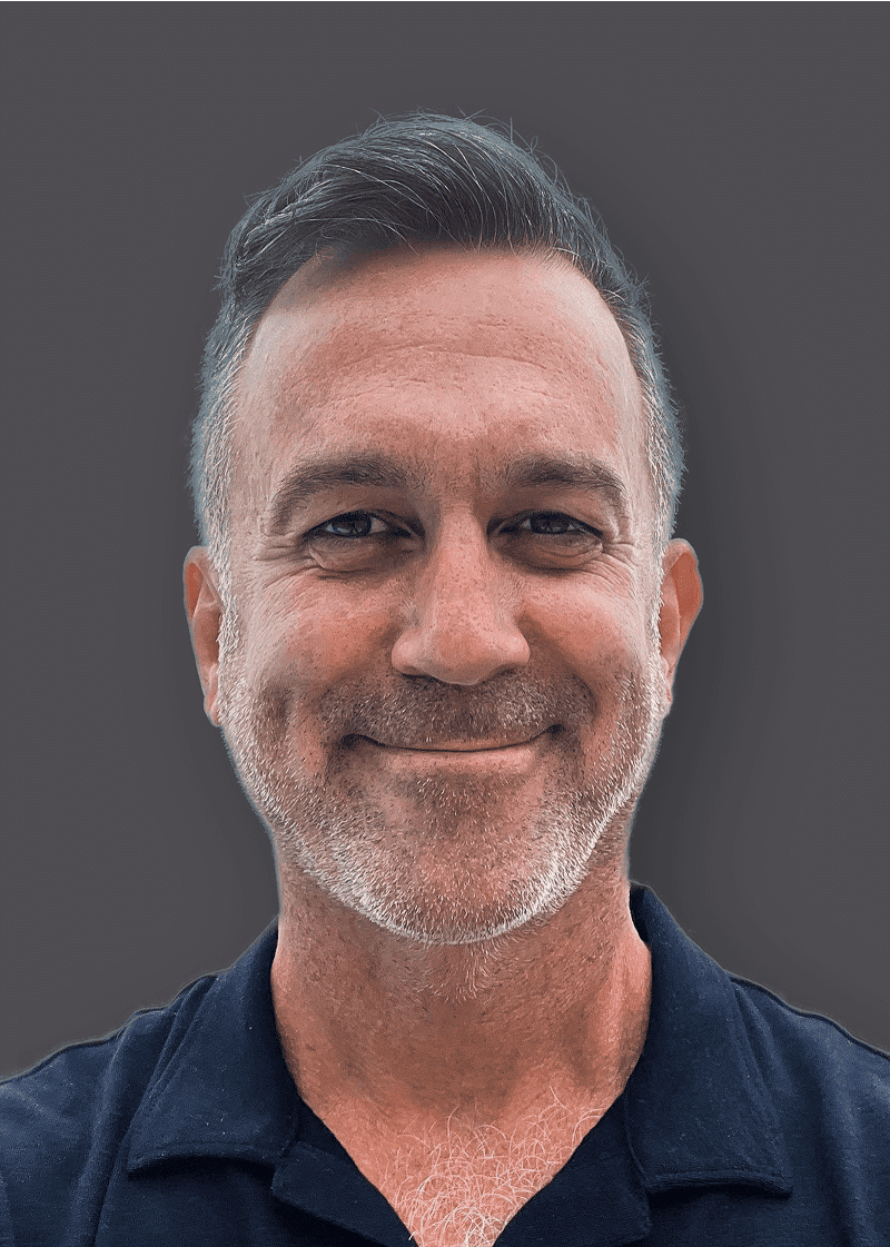 Joe Ski A smiling middle-aged man with short, dark hair, gray beard, and wearing a dark collared shirt against a gray background.